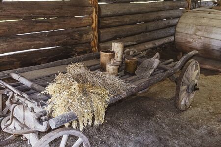 Old wooden wagon with dry ears and wooden utensils in of an shedの写真素材