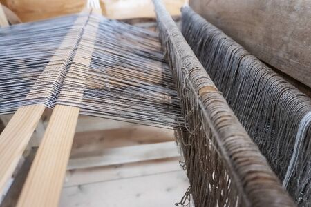 Old loom. The production of fabrics on an ancient machine. Close-up