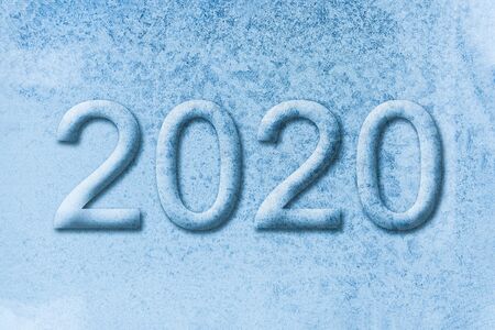Christmas background of a frozen window with the numbers 2020. Ice glass texture with the...