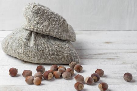 Sack with nuts on white wooden backgroundの写真素材