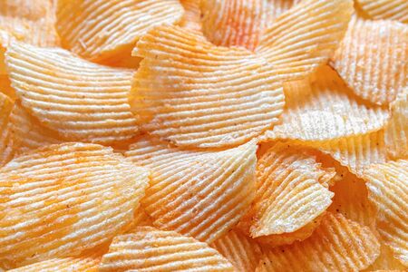 Background of corrugated fried potato chips. Top view, selective focus