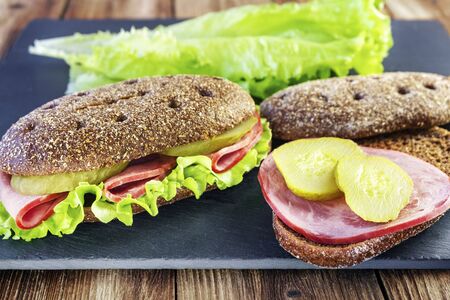 Sandwich with meat, green salad and pickles. Slices of meat and cucumber for making a sandwichの写真素材