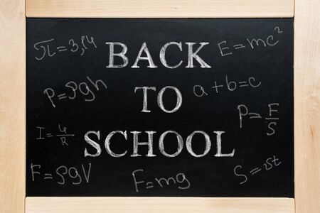 Blackboard with text written in chalk back to school and formulas