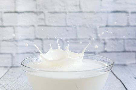 Milk splash in a glass bowl on a brick wall backgroudの写真素材