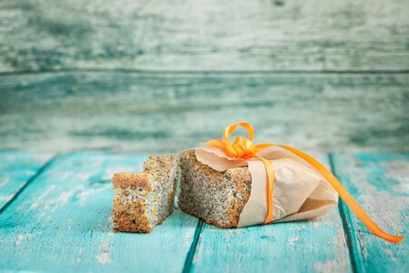 Poppy seed cake with candied orange wrapped with paper and orange ribbon on blue wooden backdroundの写真素材