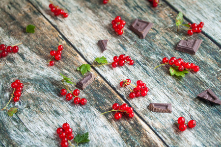 Background of ripe juicy red currant berries and chocolate slices. top viewの写真素材
