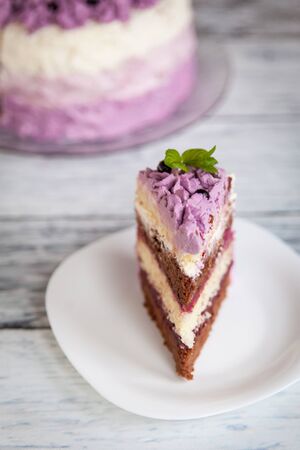 Ombre violet cake with black currants on light wooden background with purple bluebellsの写真素材