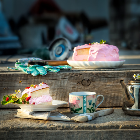 Delicate cake with strawberry surrounded by working instruments. Standing on concrete stairsの写真素材
