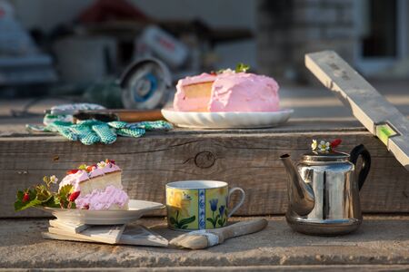 Delicate cake with strawberry surrounded by working instruments. Standing on concrete stairs