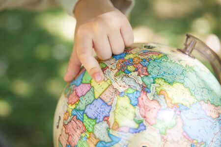 Schoolboy showing on the globe. Back to school outdoorsの写真素材