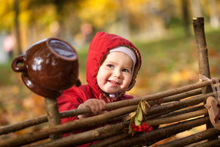 Small girl in autumn park near a wooden fence, vibrant autumn backgroundの写真素材