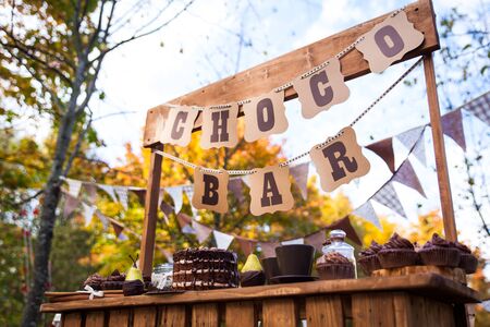 Chocolate bar stand with choco sweets, cake and other treats in autumn park