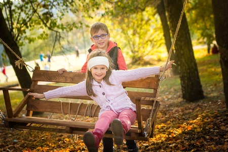Friends on the swing in the autumn parkの写真素材