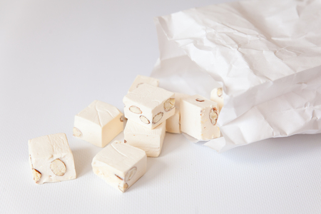 White nougat with almonds in a white paper bag on black backgroundの写真素材