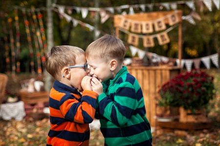 Two brothers near choco bar eating cupcake in the autumn parkの写真素材
