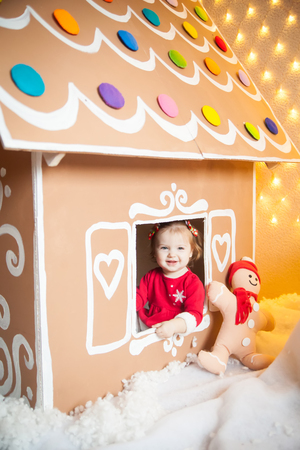Little girl looking out of the window in a gingerbread house. Christmas timeの写真素材