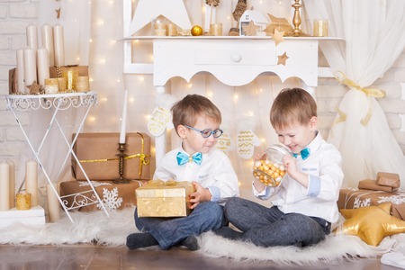 Two brothers with Christmas presents and gold candies in a glass jarの写真素材