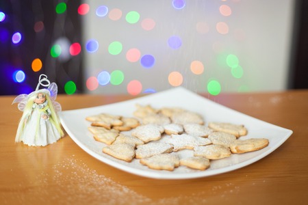 Christmas gingerbread cookies covered with powdered sugar on plate. New Year lights. Fairyの写真素材