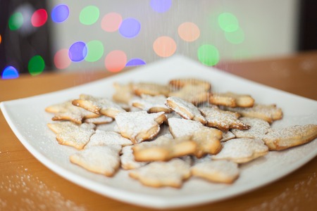 Christmas gingerbread cookies covered with powdered sugar on plate. New Year lights.の写真素材