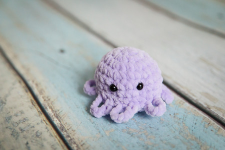 Knitted octopus toy on a color wood backgroundの写真素材