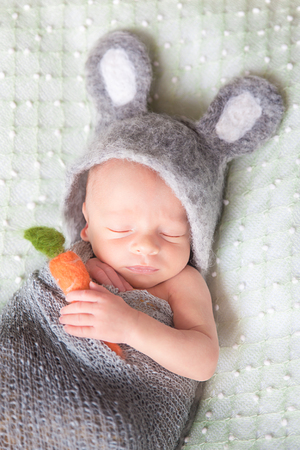 Cute sleeping newborn baby dressed like Easter bunnyの写真素材