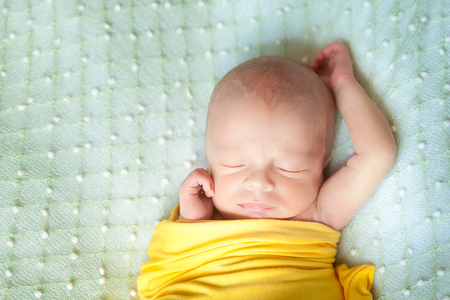 Sleeping cute newborn baby on a green blanketの写真素材