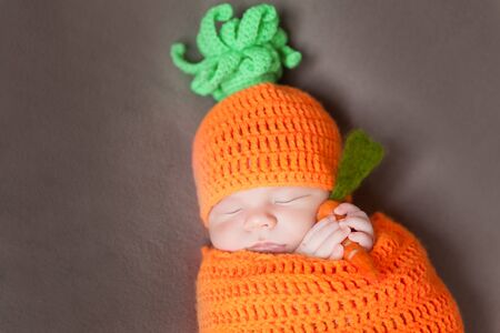 Newborn baby wearing a knitted carrot or pumpkin hatの写真素材