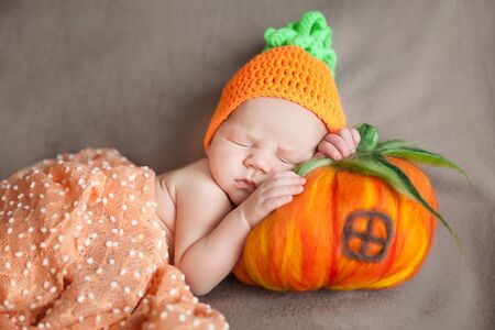 Newborn baby wearing a knitted carrot or pumpkin hatの写真素材