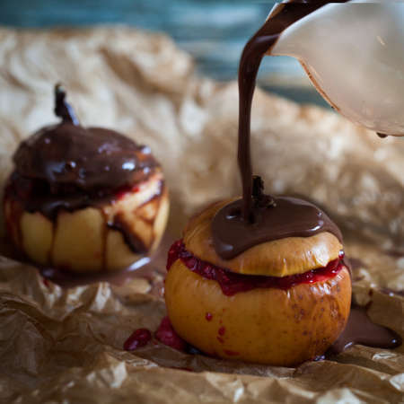 Red baked apples with walnuts and raspberry pouring with chocolateの写真素材