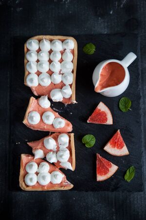 French tart with grapefruit curd and merengue on top on dark backgroundの写真素材