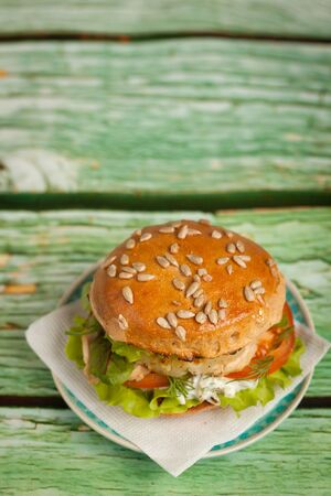 Fresh homemade burger with chicken, grilled pineapple and garlic sauce on on a green backgroundの写真素材