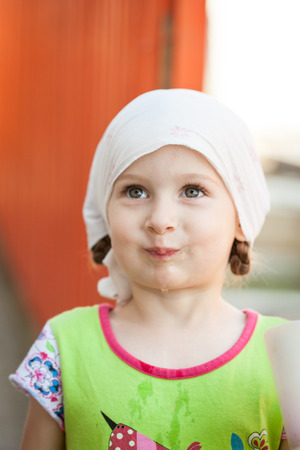 Small happy girl in a kerchief on a farm in springの写真素材