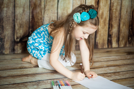 Cute girl drawing with felt-tip pens in an easter decorated studio with wooden backgroundの写真素材