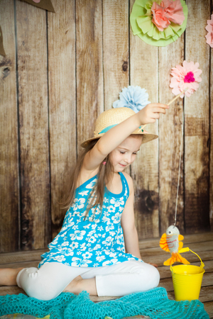 Cute girl fishing felted fishes in an easter decorated studio with wooden backgroundの写真素材