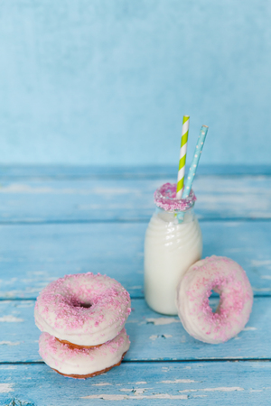 Tasty donuts with pink sprinkles with milk bottleの写真素材
