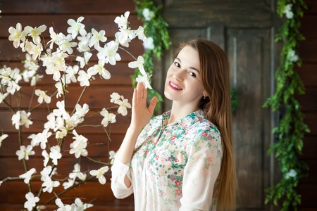 Portrait of a young woman in floral spring summer dress in a spring studio. Rustic decor