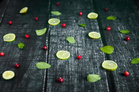 Mojito Cocktail ingredients: cranberries, mint, lime on wooden dark background. Top View food patternの写真素材