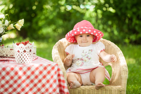 Bright summer berry party in park. Cute girl sitting at a decorated tableの写真素材