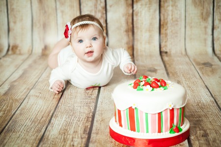 Mini birthday with strawberry theme. Cute 6 months baby girl with a sweet party cakeの写真素材