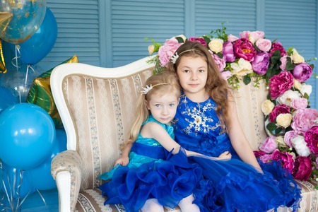 Birthday party in blue and gold collors. Studio session. Fashion girl celebrating her birthday. Two sisters having fun in the studioの写真素材