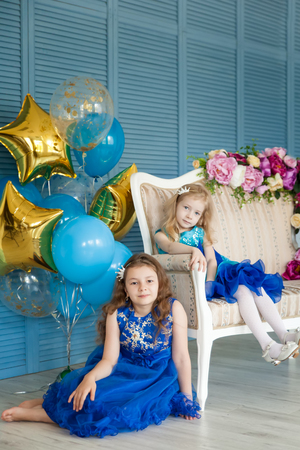 Birthday party in blue and gold collors. Studio session. Fashion girl celebrating her birthday. Two sistersの写真素材