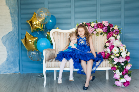 Birthday party in blue and gold collors. Studio session. Fashion girl celebrating her birthday. Two sisters having fun in the studioの写真素材