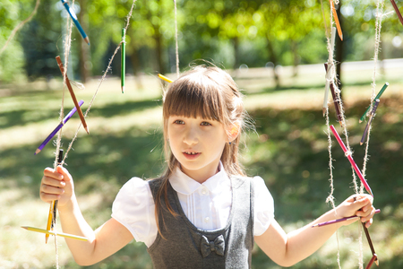 Happy little school girl in a uniform with pensil garland. Back to school outdoorsの写真素材