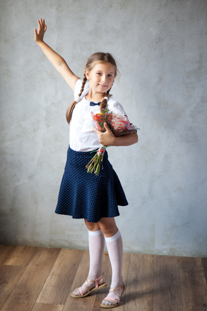 School girl in a uniform with bouquet of autumn flowers. Back to schoolの写真素材