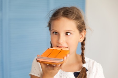 Portrait of a school girl in a uniforn crooking and eating gingerbread-pencil. Back to schoolの写真素材