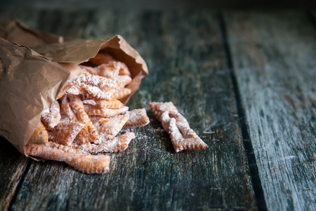 Crispy cookies Brushwood with powdered sugar in kraft paper bags on a wooden backgroundの写真素材