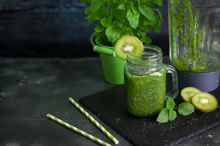 Healthy green smoothie with spinach, kiwi, banana and chia seeds in a jar mug on dark backgroundの写真素材