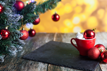 Hot coffee or tea cup with lump sugar and christmas balls. Christmas decorations, new year tree toys and fir tree branch on a dark wooden background. Golden backdropの写真素材
