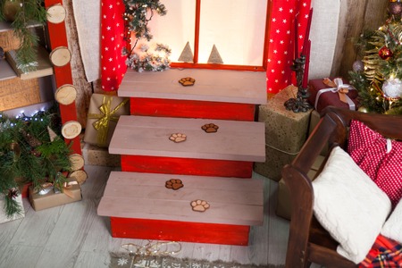 Warm christmas studio. Cosy gold and red decor, Stairs with felt footprints of puppiesの写真素材