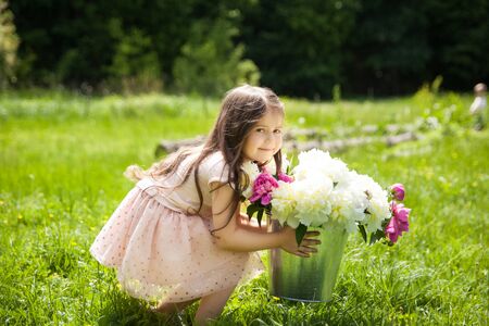 Beautiful little brunette girl with big peonies bouquetの写真素材